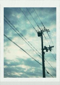 Low angle view of power lines against cloudy sky