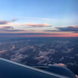 Aerial view of aircraft wing against sky during sunset