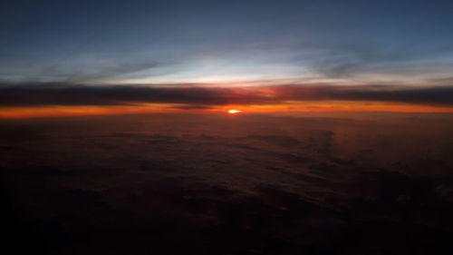 Scenic view of landscape against dramatic sky during sunset