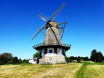 Traditional windmill on field against blue sky