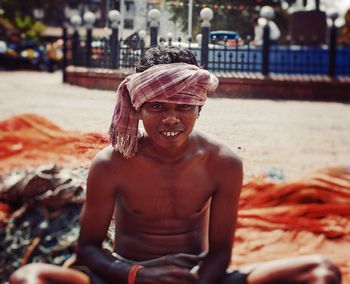 Portrait of smiling shirtless man with towel wrapped on head at city street