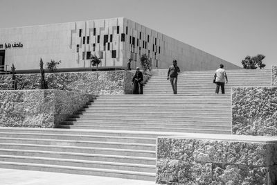 People walking on staircase against building
