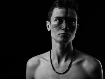 Portrait of young man against black background