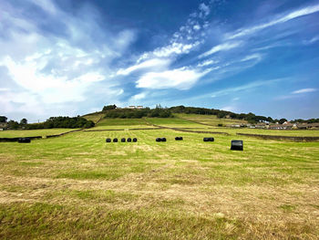 Bales of hay, in an extensive meadow, with trees, and houses on the horizon in, warley, halifax, uk