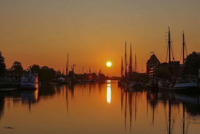 Boats moored at harbor during sunset