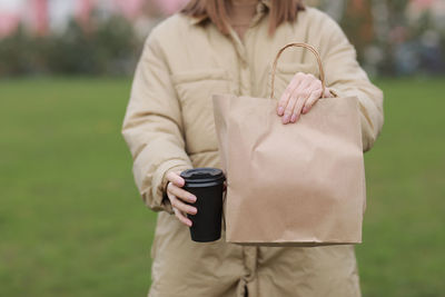 Midsection of woman holding umbrella standing on field