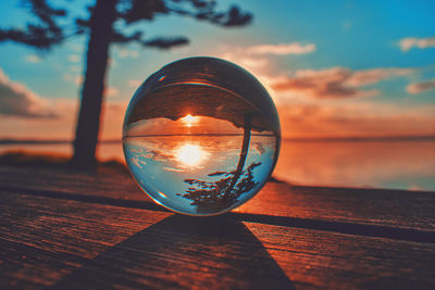 Close-up of illuminated lensball on table against sky during sunset
