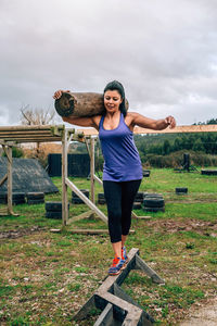 Full length of woman exercising with log on field