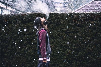 Young woman standing on tree against sky