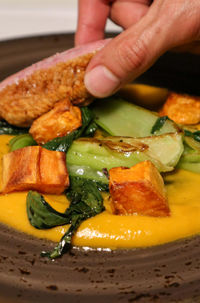 Close-up of hand holding food in plate