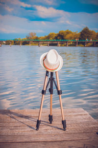 A tripod covered with a hat on the wooden pier of the pier. concept of rest.