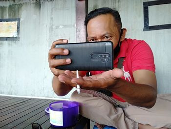 Portrait of man photographing with mobile phone