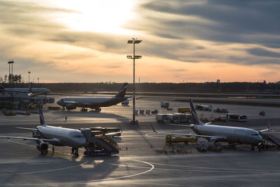 Airplane on airport runway against sky during sunset