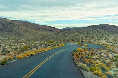 Road leading towards mountains against sky