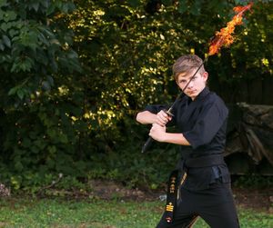 Young boy standing in front of trees with sword