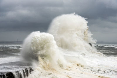 Gigantic waves splashing on harbour pier against stormy sky