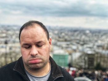 Close-up of tired man standing against cityscape