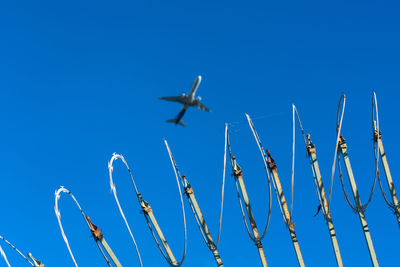 Low angle view of airplane flying against clear blue sky