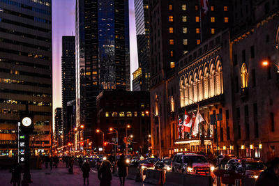 People on city street amidst illuminated buildings at night