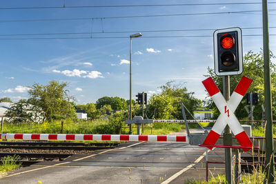 Guarded railroad crossing with closed barriers, red warning light and cross of saint andrew.