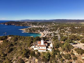 High angle view of townscape by sea against clear blue sky