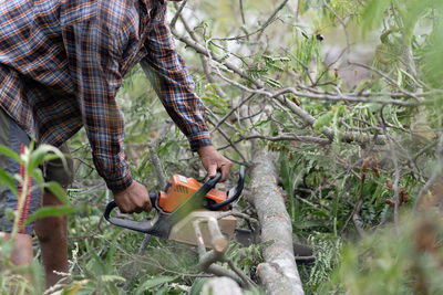 Midsection of man cutting log with circular saw