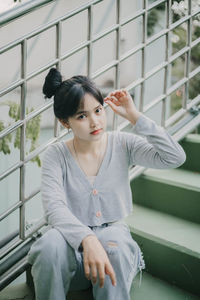 Portrait of woman sitting on railing