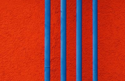 Full frame shot of red wall with blue pipes