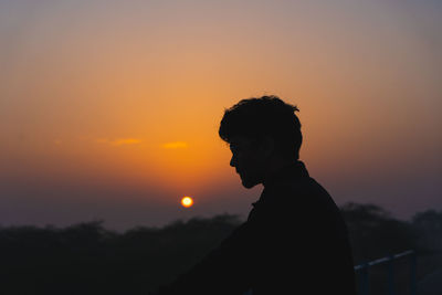 Silhouette man standing against orange sky