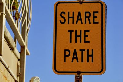 Low angle view of road sign against blue sky