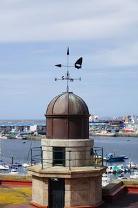 Ship moored at harbor by building against sky