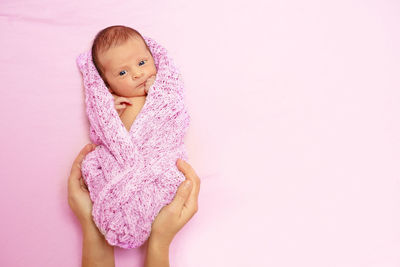 Portrait of young woman standing against pink background