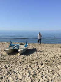 Deck chairs on beach against clear sky