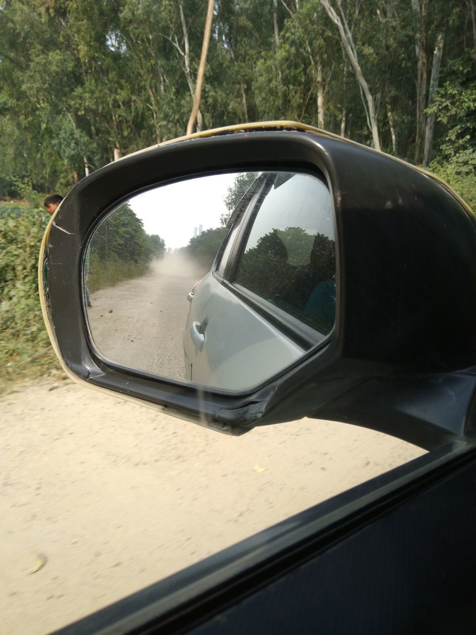 REFLECTION OF CAR ON SIDE-VIEW MIRROR OF ROAD