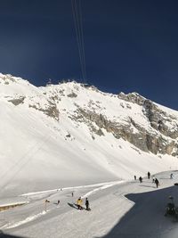 People skiing on snowcapped mountain against sky