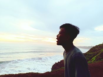 Side view of man looking at sea against sky