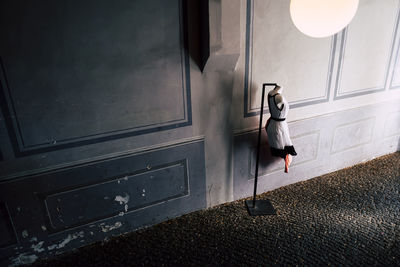 Side view of woman  dress standing near a wall