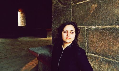 Portrait of beautiful young woman standing against wall