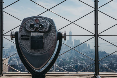 Close-up of coin-operated binoculars against cityscape