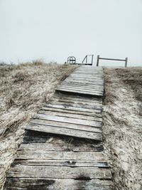 Steps leading towards sand against clear sky