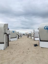 Hooded chairs on beach against sky