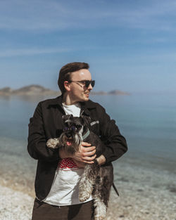 Portrait of young man with dog at beach