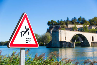 Information sign by road against clear blue sky