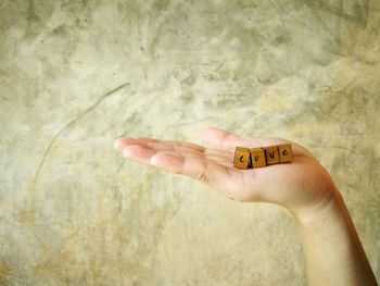 Cropped hand holding love text on wooden cubes against wall