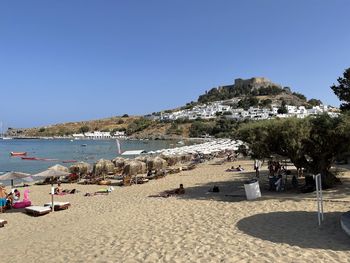 People on beach against clear sky