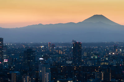 Illuminated buildings in city at sunset