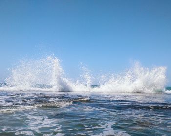 Water splashing in sea against clear blue sky