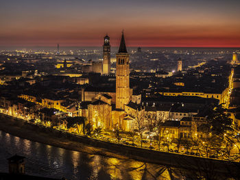 Illuminated buildings against sky at dusk