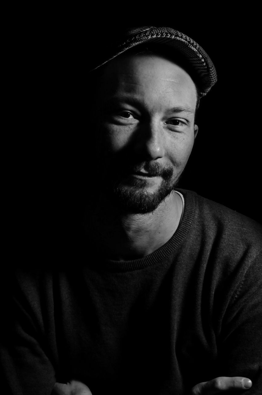 young adult, portrait, looking at camera, young men, person, lifestyles, front view, headshot, indoors, casual clothing, studio shot, leisure activity, serious, mid adult, black background, mid adult men, contemplation, beard