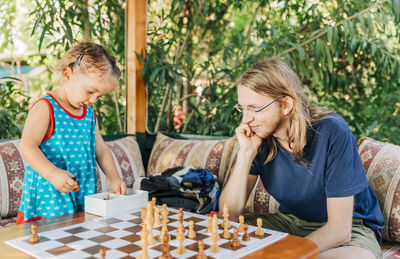 Father and daughter playing chess on table